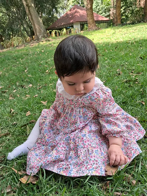 Sofía Anahí sentada en el pasto con vestido de flores